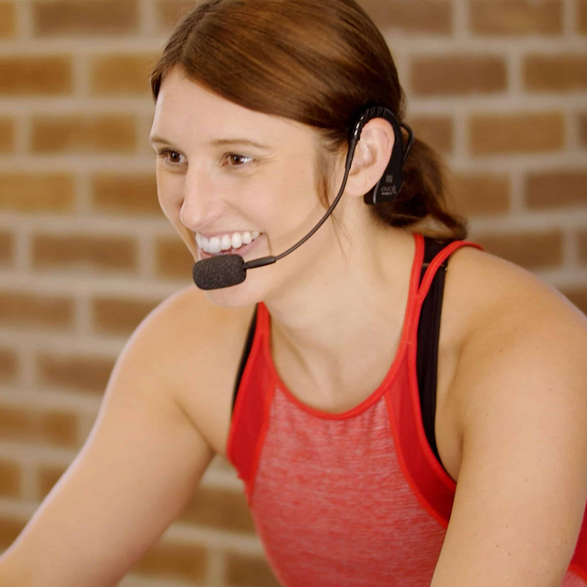 Fitness instructor in spin class working out with participants and using the EVO cableless headset mic
